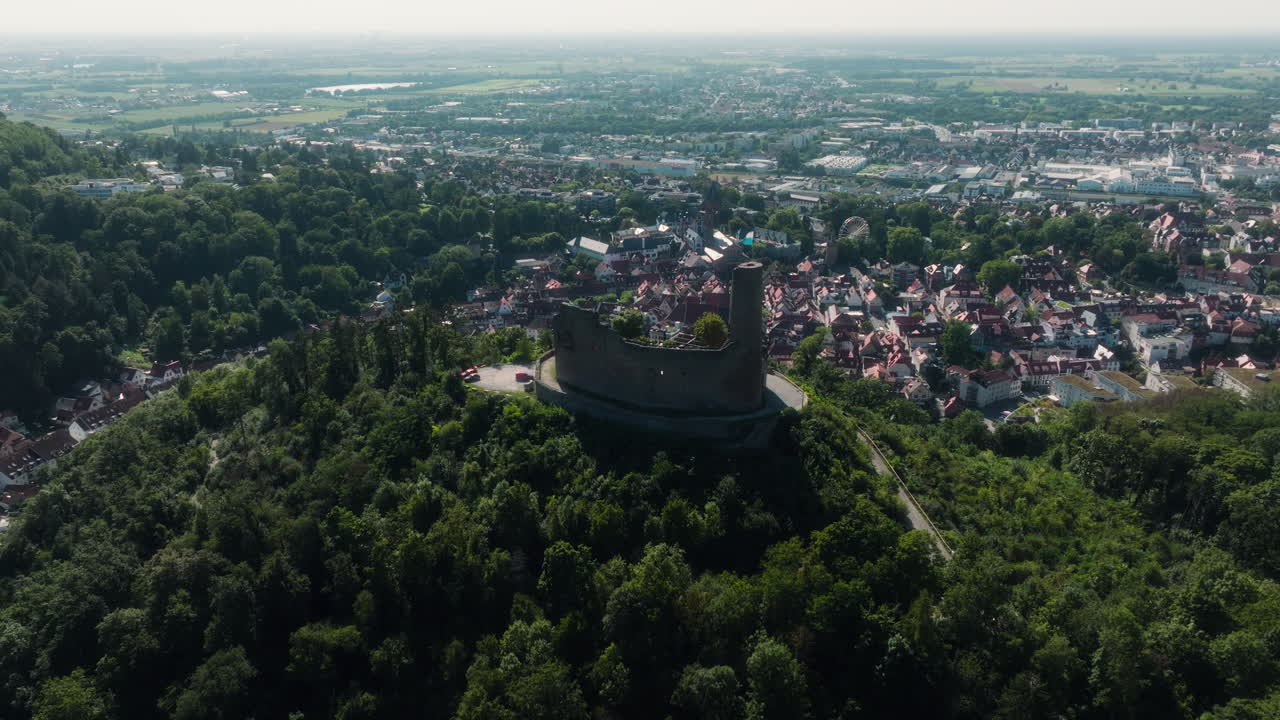 Drone panning behind Dilsberg Castle overlooking Heidelberg, Germany, with the castle in backlight and the valley filled with houses under the evening sun