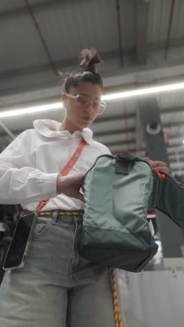 young woman looking at a backpack in a store