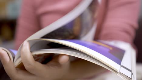 detalle de una mujer hojeando una revista sentada en un sofá
