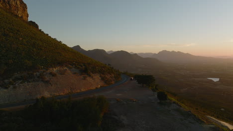 Cinematic-shot-of-mountain-landscape-in-sunset-time.-Road-and-resting-place-with-lookout-point-above-valley.-South-Africa