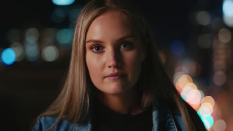 retrato de una hermosa joven mujer caucásica en el techo por la noche con luces de la ciudad bokeh en el fondo del horizonte urbano