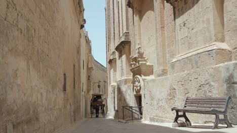 Rear-View-Of-Horse-Drawn-Carriage-With-Tourist-Passengers-Traveling-On-Narrow-Medieval-Street-In-Mdina,-Malta