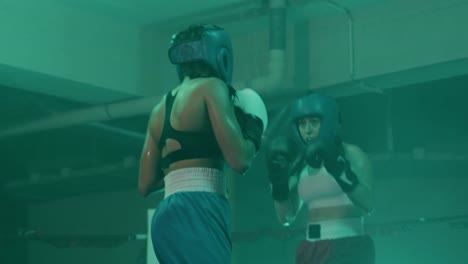 two female boxers in helmets and boxing gloves training in ring