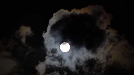 eerie night sky unveiled: full moon timelapse with ominous clouds casting shadows over a bright moon, shrouded in dark dust