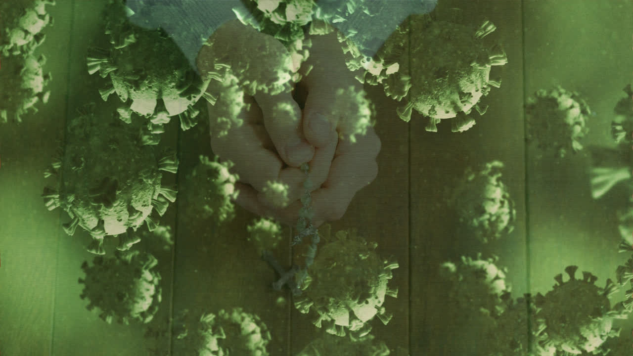 células de covid-19 moviéndose contra las manos orando y sosteniendo el rosario