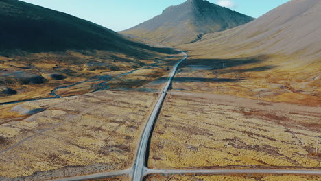 Drone-footage-of-car-driving-down-a-road-in-dramatic-valley-in-Iceland