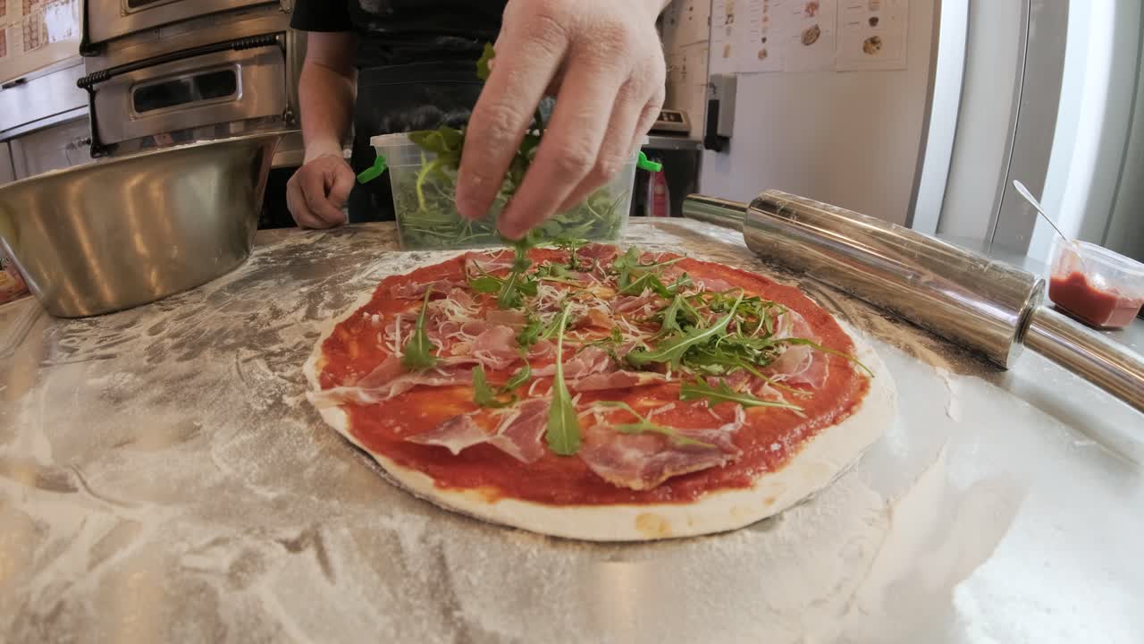 요리사는 피자를 만들고 허브를 뿌립니다.