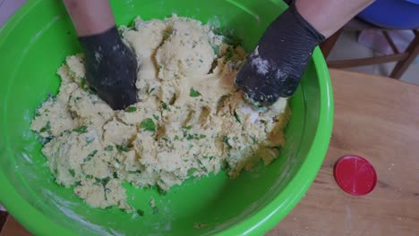 Mixing-stuffing-in-a-large-bowl-while-making-flaouna,-a-traditional-cheese-filled-pastry-in-Cyprus,-Greece