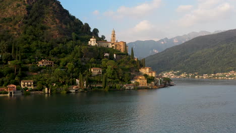 Drohnenaufnahme-Der-Kirche-Santa-Maria-Del-Sasso-In-Der-Schweiz,-Die-über-Den-Luganersee-Fliegt