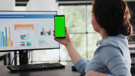 Employee-holding-mobile-phone-at-desk