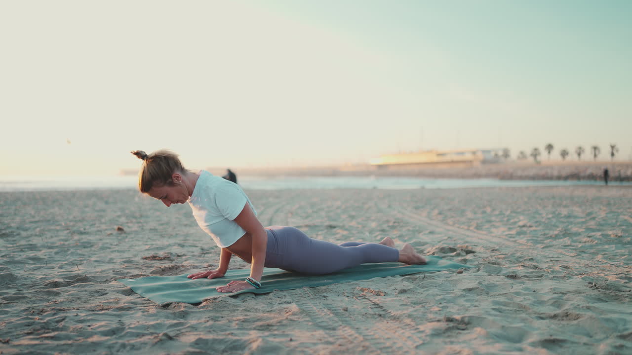 una foto de larga duración de una mujer deportiva haciendo yoga en una alfombra junto al mar.