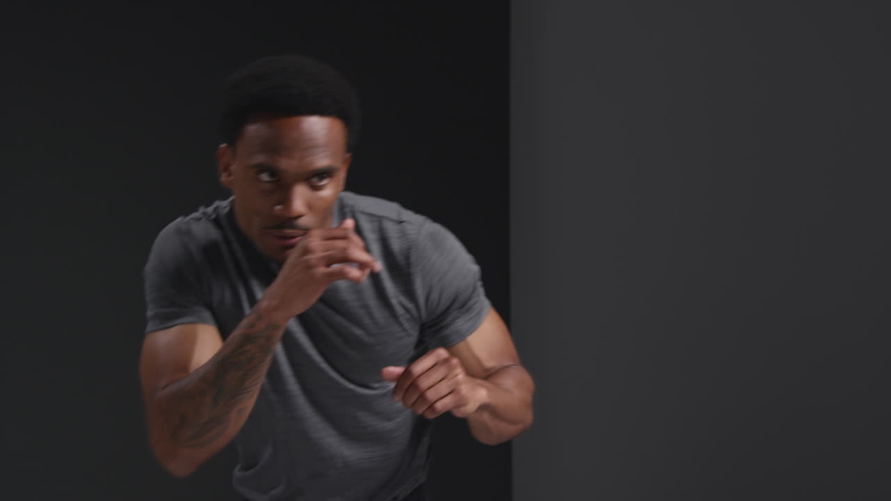 남자 권투 선수가 체육관에서 훈련하고, 스파링을 하고, 몸을 따뜻하게 하고, 검은 바탕에 맞서 싸우기 위해 준비하는 모습.