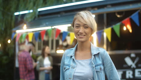 Close-Up-Of-Pretty-Blond-Young-Woman-With-Short-Hair-Smiling-Cheerfully-To-Camera-Outdoor