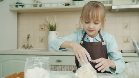 young girl kneading dough in a kitchen