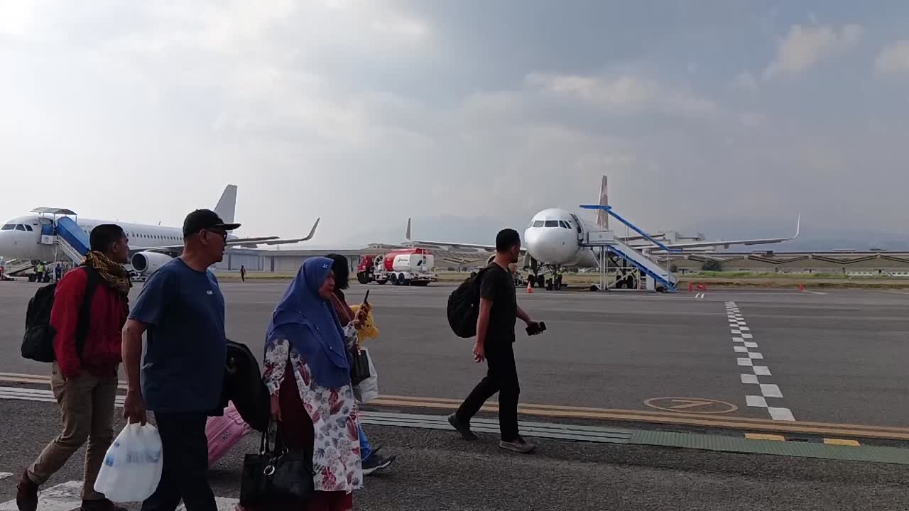 Passengers walk off the plane at Husein Sastranegara Airport. slow motion.