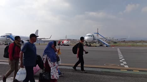 passengers walk off the plane at husein sastranegara airport. slow motion.