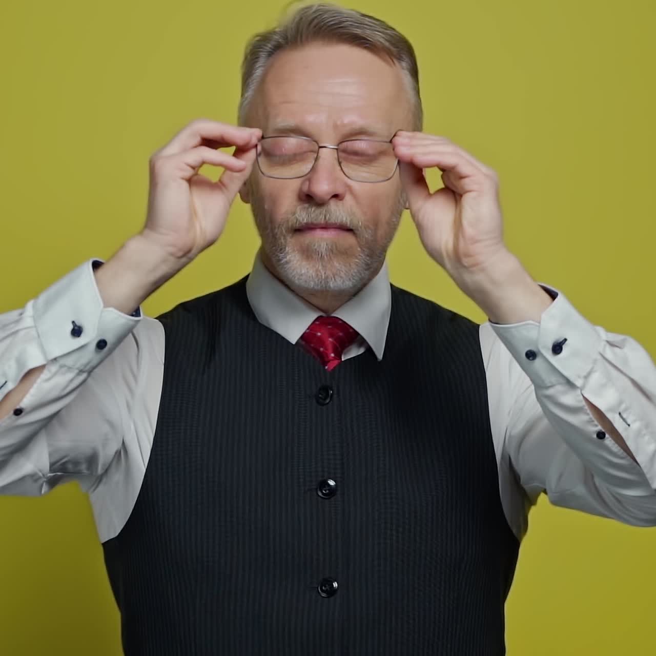 Funny grey-haired man with glasses. Portrait of a mature man in suit putting on glasses with a funny view. Slow motion. Positive emotions.