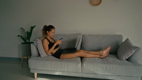 woman relaxing on couch with phone and laptop
