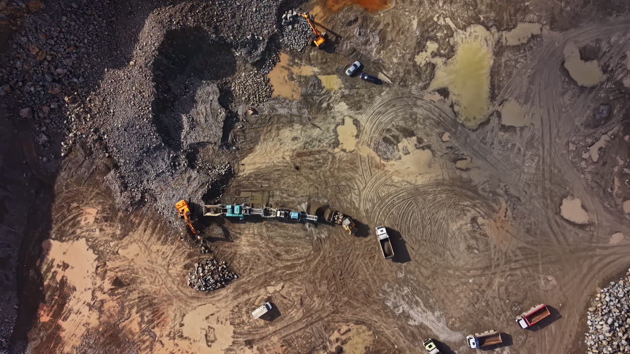 Granite quarry operation in large excavation site with multiple vehicles working in an outdoor environment