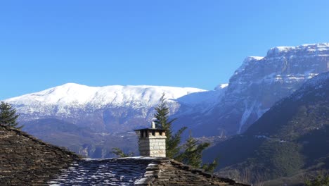 希腊扎戈里 (zagori) 传统的石头屋顶,背景是雪山