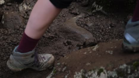 rear view of a female tourist's leg in trekking boots climbing up the rocks