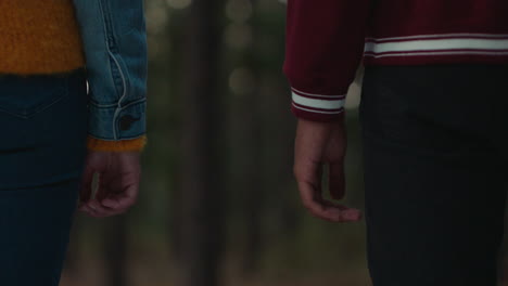 teenage couple holding hands in forest at sunset boyfriend playfully holds girlfriends pinky finger sharing romantic connection in woods happy young lovers