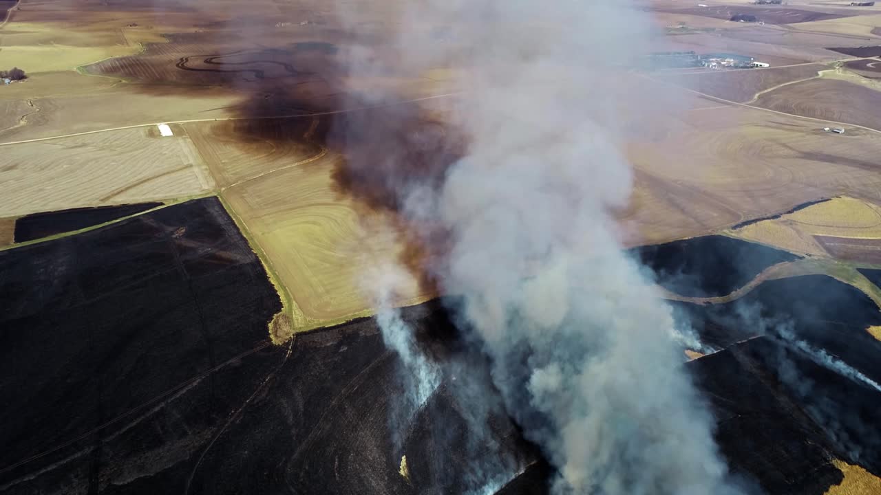 vista aérea de una gran nube de humo y praderas en llamas rodeadas de tierras de cultivo