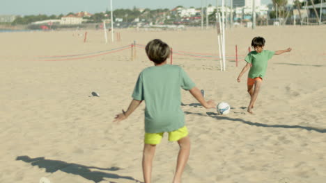 long shot of focused boy hitting ball to goalkeeper on shore