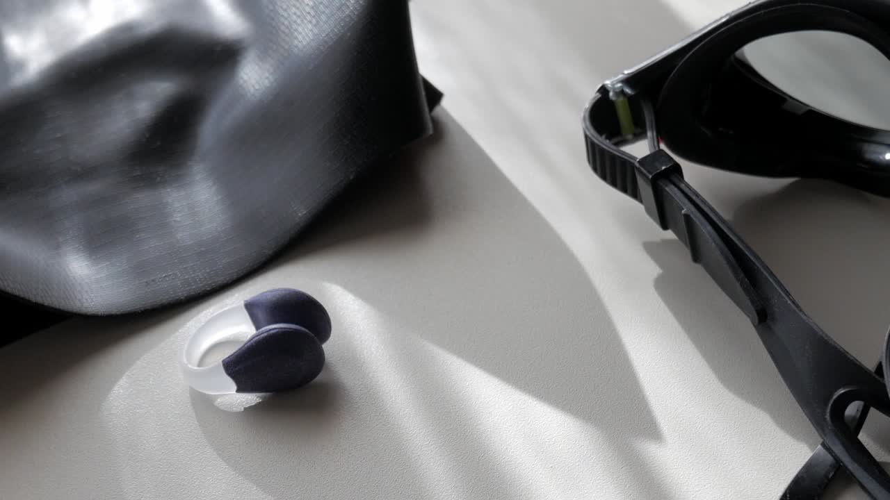 Swimming goggles, earplugs, and a swim cap arranged neatly, ready for use