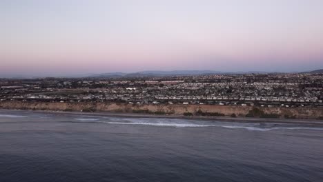 Un-Hermoso-Disparo-Aéreo-De-Drones,-Volando-Hacia-La-Costa-Con-Vistas-A-Una-Ciudad,-El-Horizonte-Y-Las-Montañas,-Playa-Estatal-De-Carlsbad---California