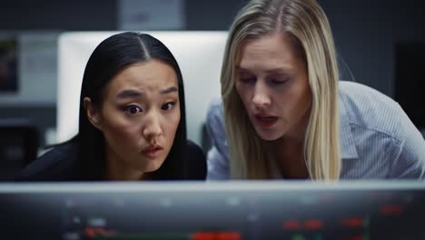 two professionals focus intently on displays in a sleek office space at night, collaborating to interpret complex data to make informed decisions for their project.