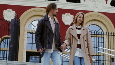 couple walking hand-in-hand in front of a building