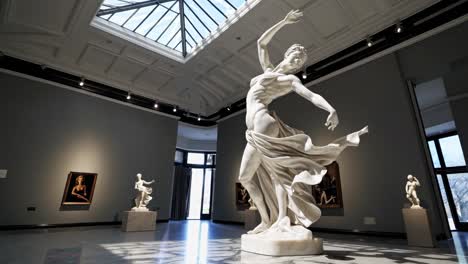 a dynamic low-angle video shot of a marble statue in a gallery, highlighting its graceful form