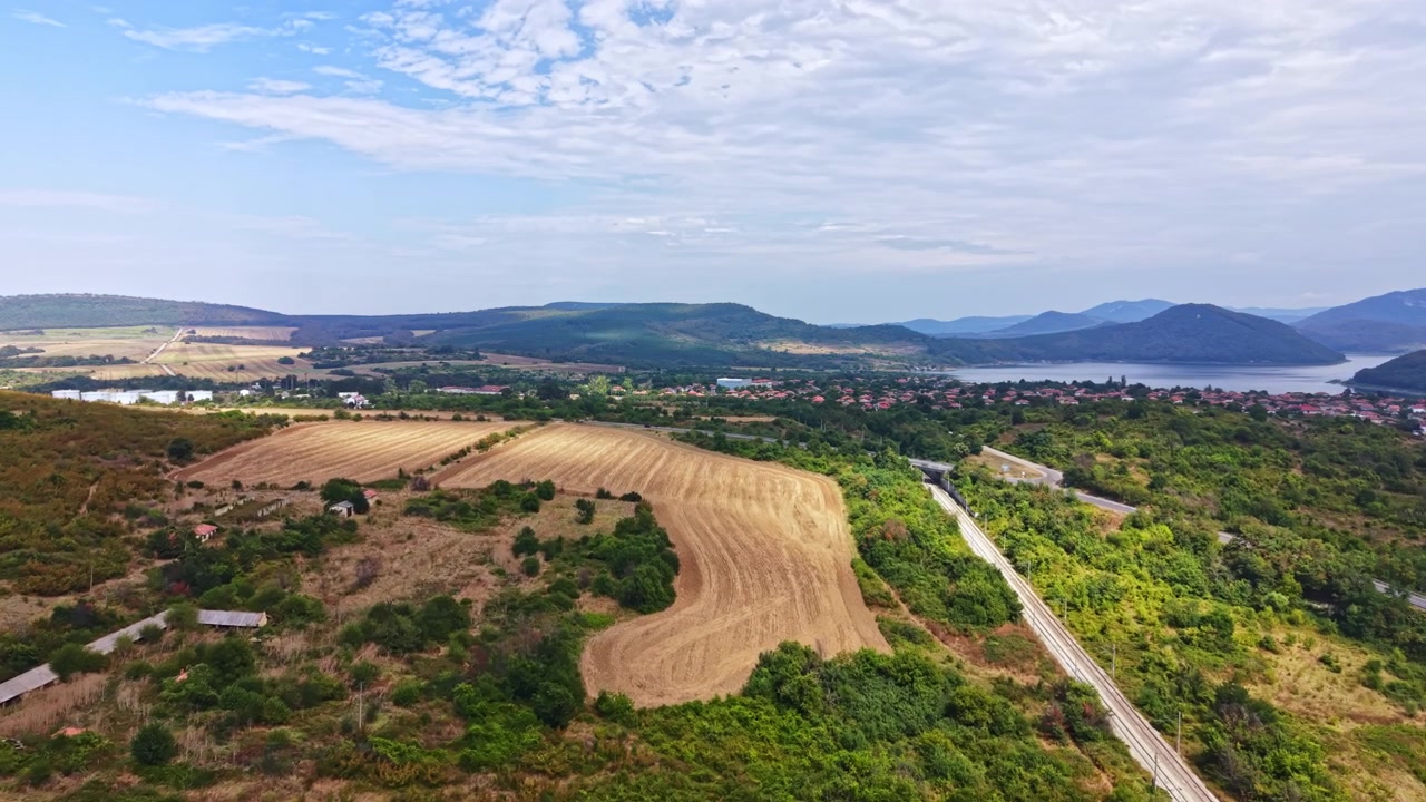 Vista panoramica di campi coltivati e colline vicino a uno specchio d'acqua in una zona rurale durante il giorno