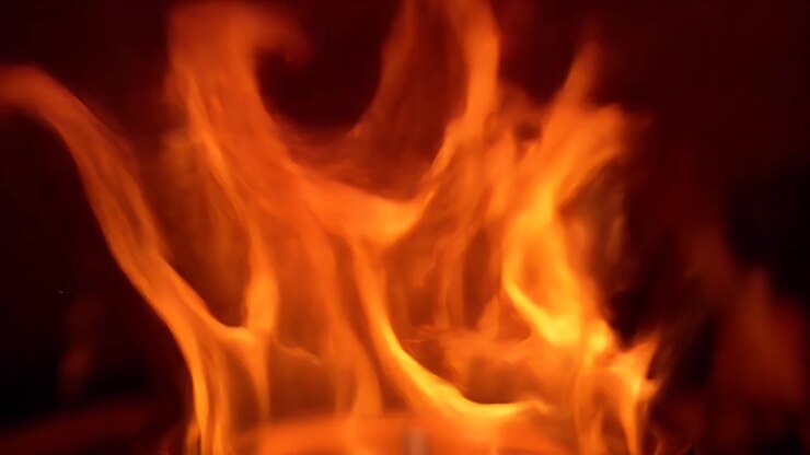 Primer plano de llamas naranjas brillantes ardiendo en una chimenea