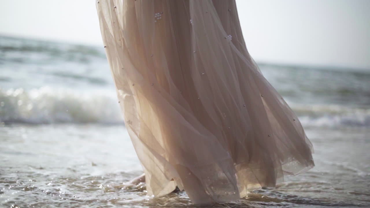Slow motion.Women walking barefoot by the beach while the sun sets.Waves at sunset.