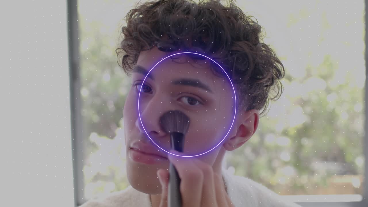 Man starting brushing right cheek with brush, blending on face, neon shapes framing face for makeup