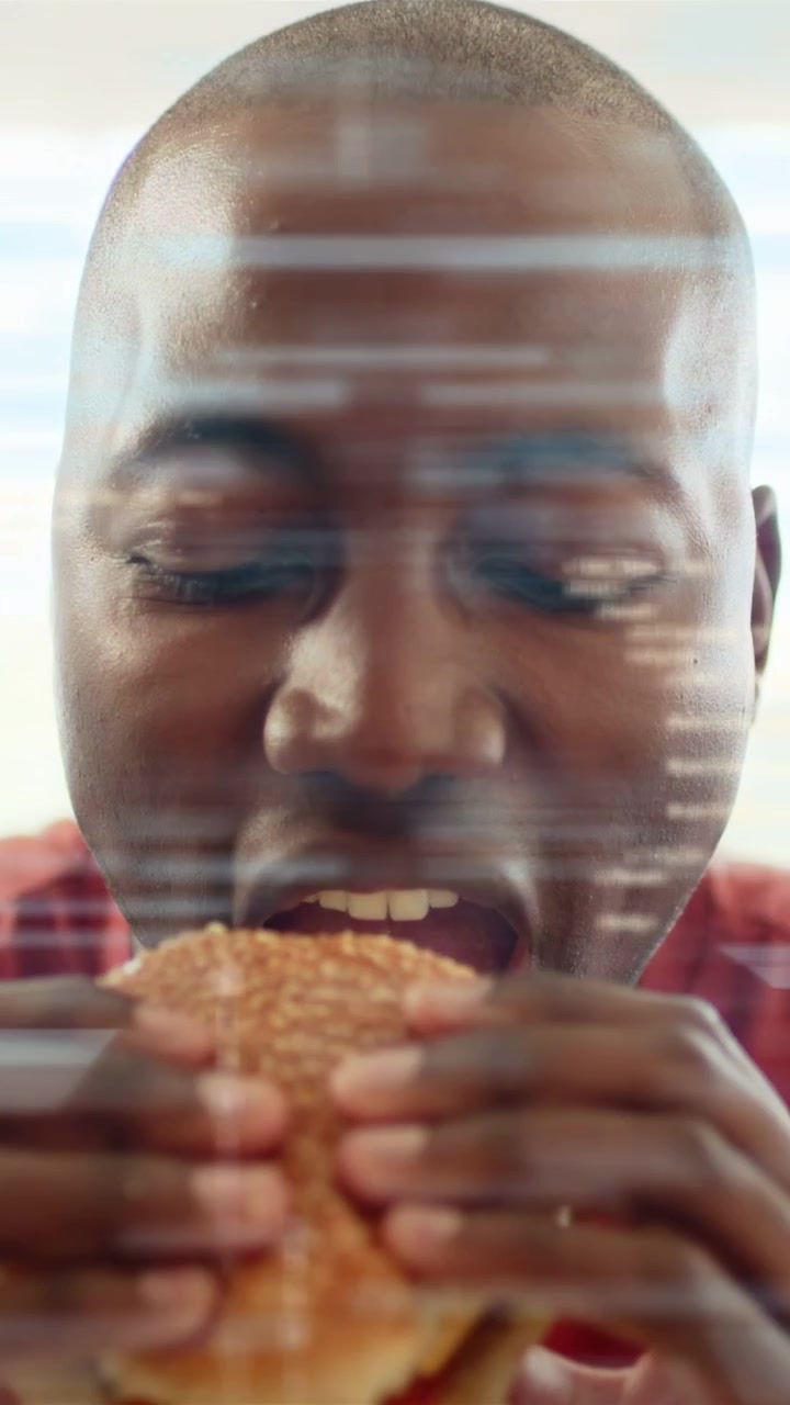 Video vertical: Hombre observando un sándwich, mordiendo en primer plano mientras aparecen barras de interfaz de usuario de alimentos y una superposición binaria, degustando.