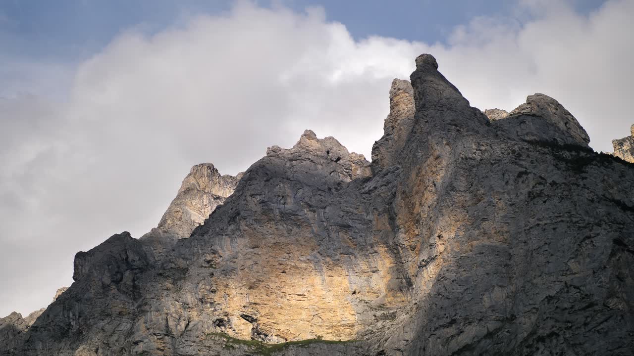 Clouds moving on the background of the bare tops of a mountain in Lauterbrunnen Switserland while the sun and shadows are reflected. Wide shot
