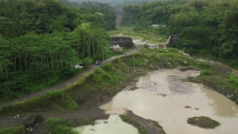 drone shot of truck crossing road beside lake former sand mine in wilderness of indonesia