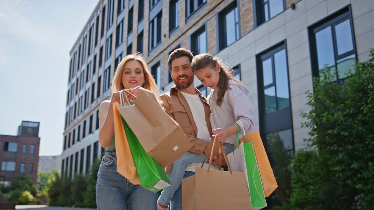 Family walking shopping bags on city street. People strolling with paper bags