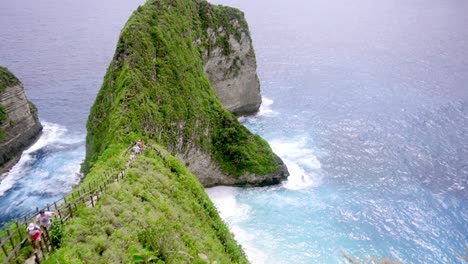 Cinematic-reveal-over-fence-shows-luxurious-blue-waters-of-Kelingking-beach-nusa-penida-bali-indonesia