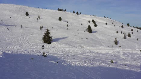 Lonely-hiker-walking-along-a-snow-covered-path-in-a-mountain-wilderness-in-the-alps