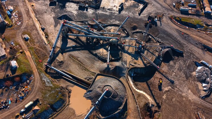 Working construction site. Heavy machinery moves materials at a construction site during daylight in an open area with piles of gravel and dirt