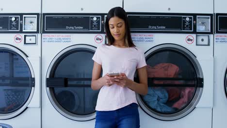 mujer usando teléfono móvil en la lavandería 4k