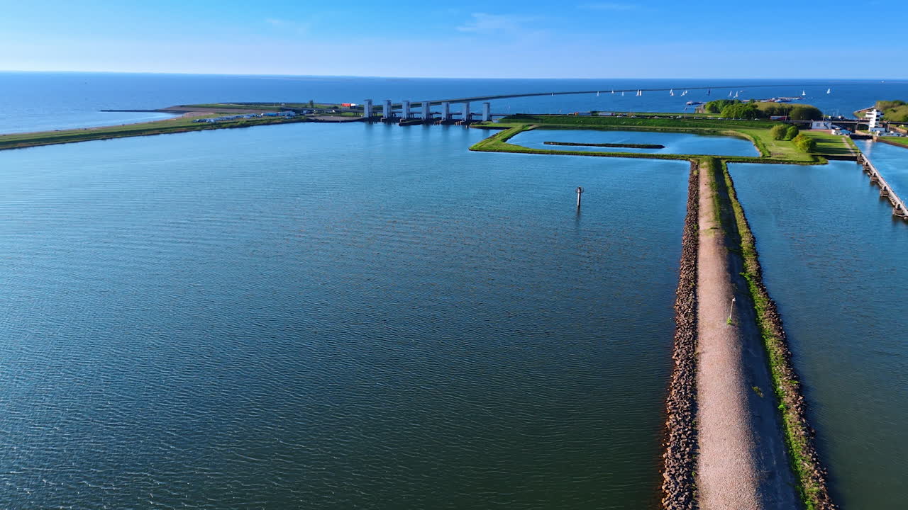 Waterscape of lake Markermeer with dikes and sluices. Multiple sailboats at on the water backdrop. Aerial view.