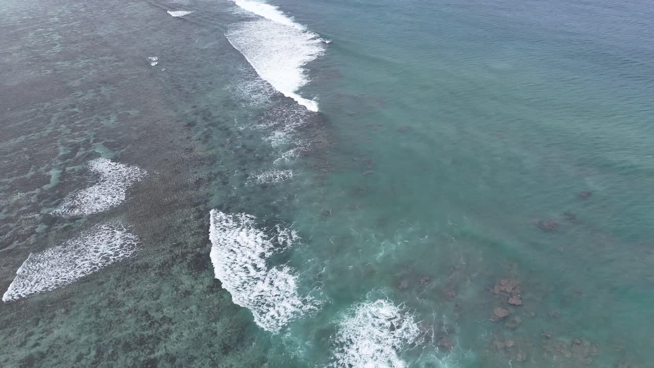 Pemandangan udara dari drone ke terumbu karang dan ombak yang menerjang di Pasifik Selatan, Tonga. Perairan biru kehijauan yang memukau dan ombak putih yang diambil dari atas di pulau tropis terpencil yang indah