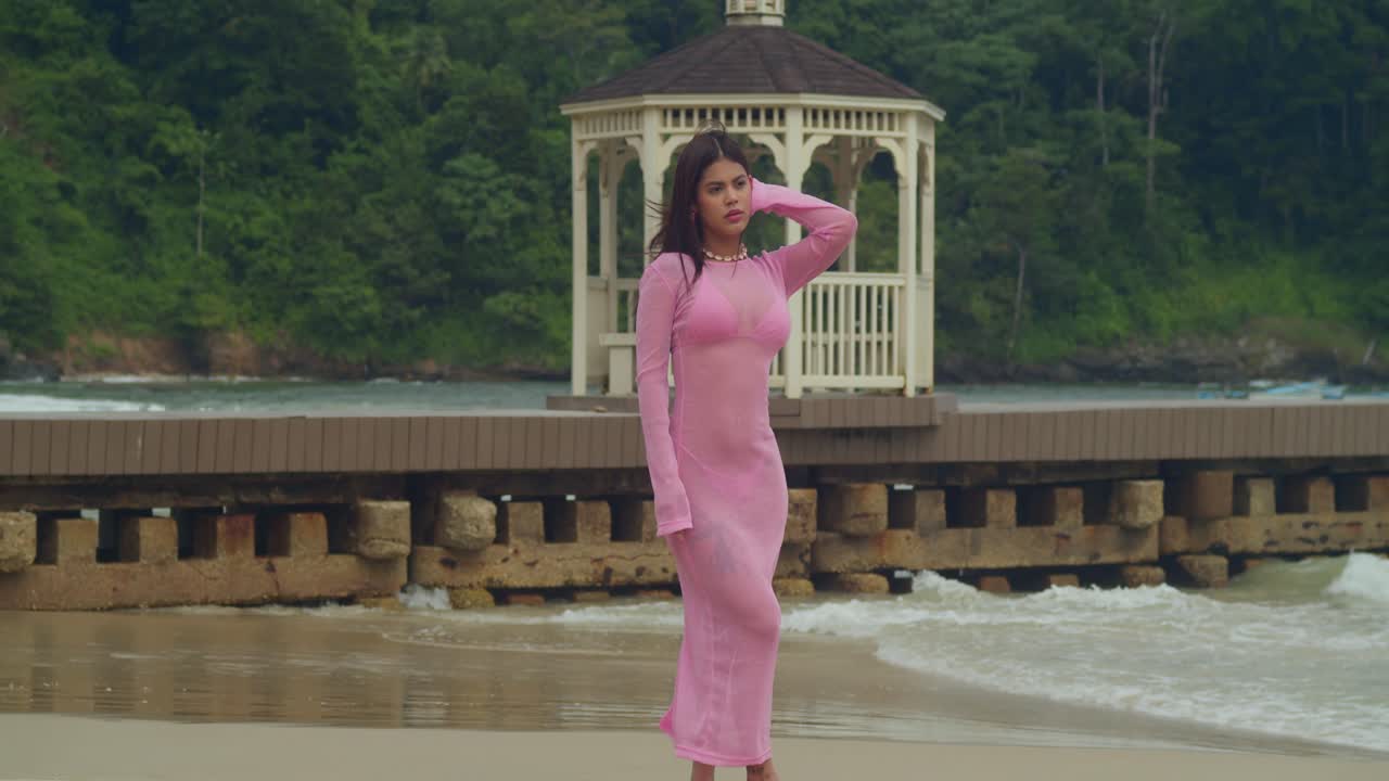 She stands at the water's edge in her swimwear, looking out at the emerald horizon of Trinidad’s coastline