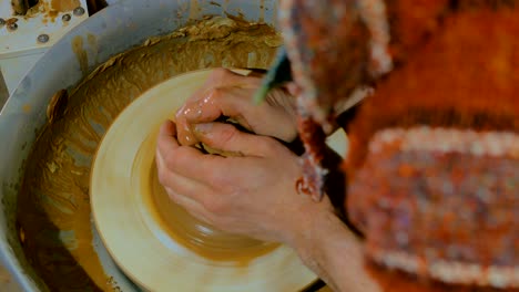 professional male potter working with clay on potter's wheel