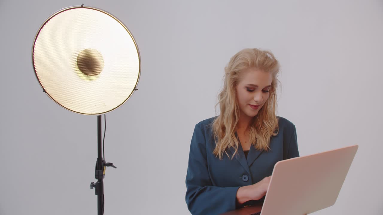 девушка работает на ноутбуке в студии на белом фоне